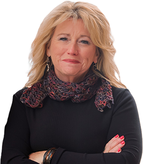 Portrait of a blonde woman in a black top and patterned scarf, arms crossed, smiling softly at the camera.